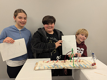 Three students behind the bridge they built