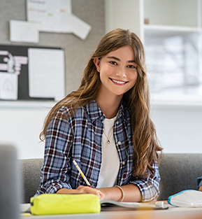 Happy high school student smiling at her desk in a classroom