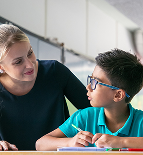 Cheerful teacher checking in with a student at his desk